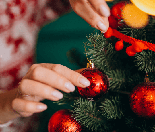 Une femme mettant une boule de Noël rouge montrant sa manucure, photo de collection de kit de faux ongles Noël