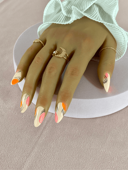 Kit de faux ongles réutilisables à coller avec des adhésifs de couleur nude avec des designs variés, incluant des motifs abstraits, ligne, points, rond orange et rose.