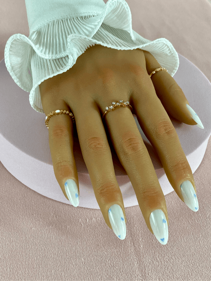 Kit de faux ongles réutilisables avec des designs variés, incluant des petits coeurs bleu clair, couleur principale blanc, en forme d'amande.