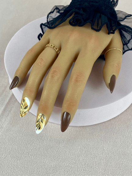 Faux ongles réutilisables, couleur marron, en forme d'amande, avec motif de feuilles noir et or, fini mat et brillant pour un look sophistiqué et naturel.