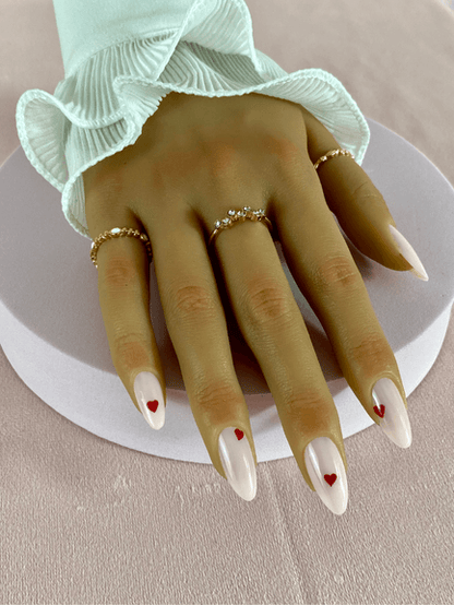 Ensemble de faux ongles réutilisables avec des petits coeurs rouges, la couleur principal des ongles en formes amande est rose clair, un look à adopter lors de la Saint Valentin ! 