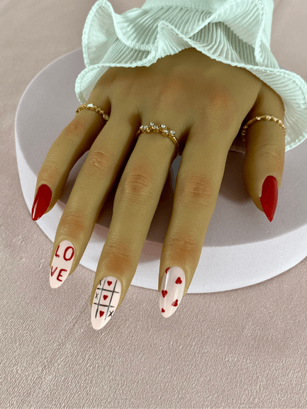 Ensemble de faux ongles réutilisables à coller avec des adhésifs avec des motifs morpion, petit coeurs rouges et une inscription "love", de forme amande.