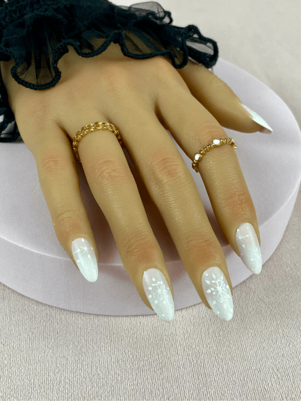 Faux ongles réutilisables, nude et blanc et longs, avec un baby-boomer et des flocons de neige, pour une manucure audacieuse et chic.