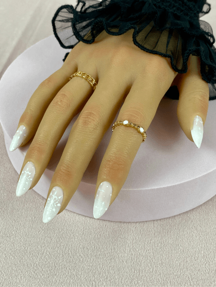 Faux ongles réutilisables, nude et blanc et longs, avec un baby-boomer et des nail art de Noël, pour une manucure audacieuse et chic.