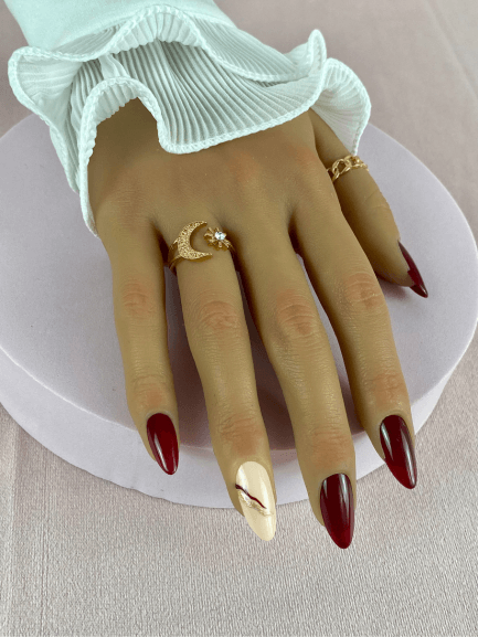 Ensemble de faux ongles réutilisables couleur bordeaux avec des lignes bordeaux et rose pailleté, en forme de amande, pour un style moderne et glamour.