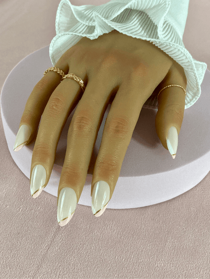 Kit de faux ongles réutilisables à coller à l'aide d'adhésifs avec des designs variés, incluant des French manucure de deux couleurs qui sont le blanc et rose clair terminant par une ligne d'or, la forme des ongles est amande.